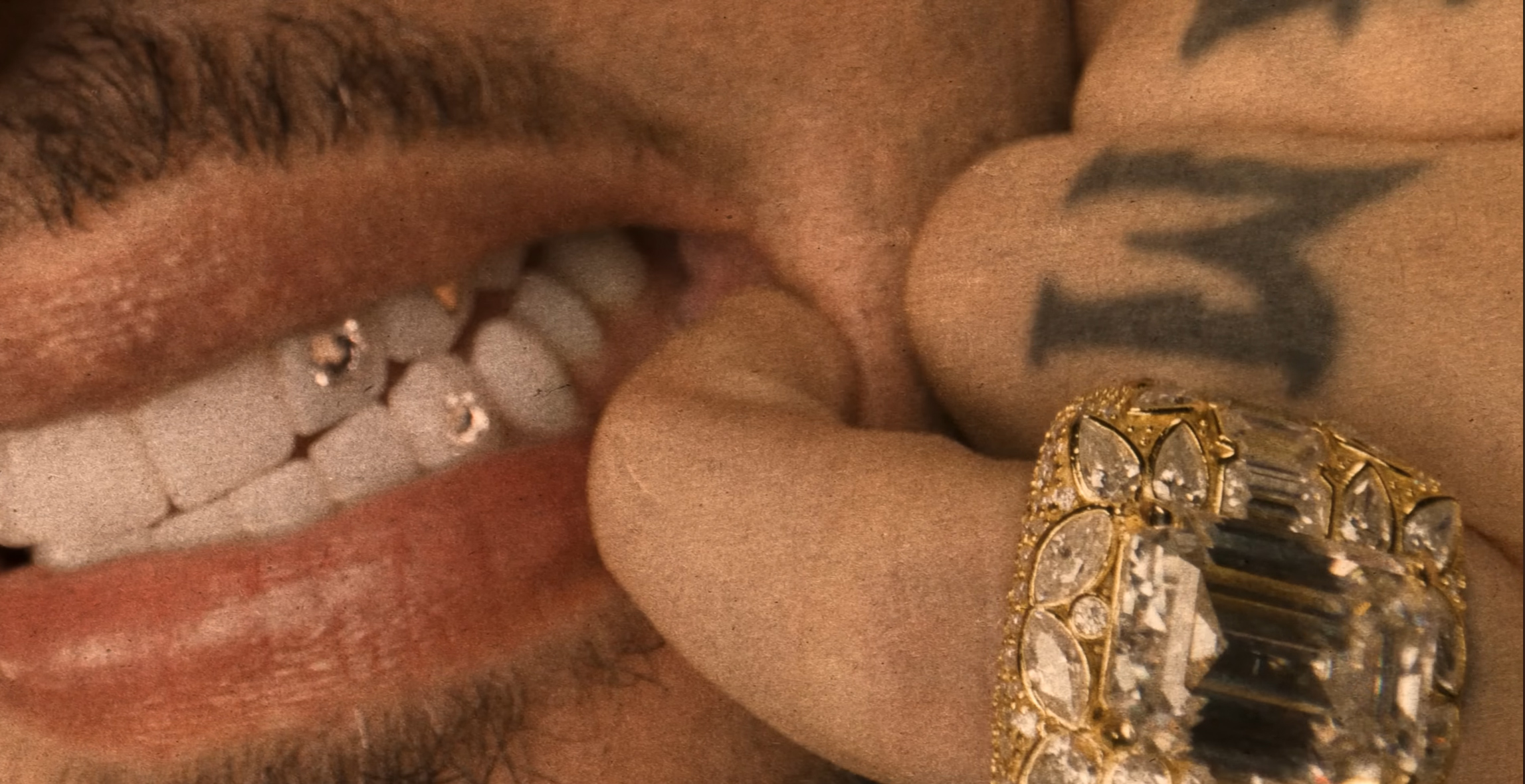 Close-up of a smile, jeweled teeth and a gold ring in warm light