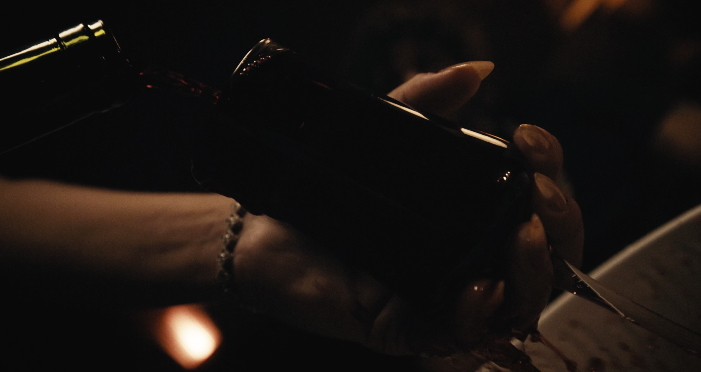 Hands holding a dark bottle in warm cinematic light
